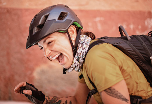 a female cyclist wearing a helmet laughs and smiles with joy