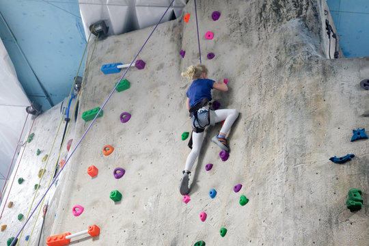 young girl climbing rock wall at indoor rock  climbing gym