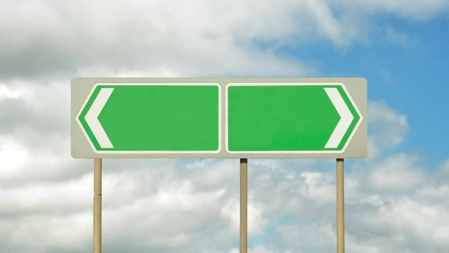 A blank road signs of a road dividing in opposite directions with a background of time lapse blue sky and white clouds. Making a choice. Going no where. Split to an empty future.
