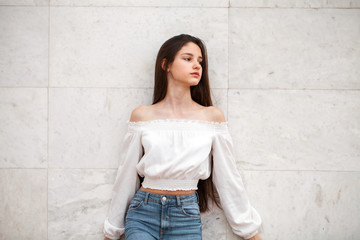 Young beautiful girl on a background of a white marble wall