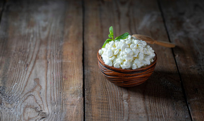 Granulated cottage cheese in a ceramic bowl on a wooden background. Healthy eating concept.