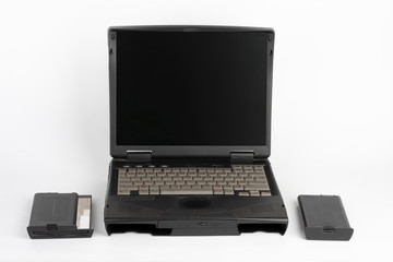 16 year old notebook, floppy disk drive and laptop battery on white background