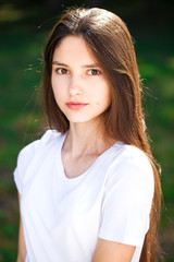 Fototapeta premium Исфдьeautiful brunette girl in white t-shirt on a background of a summer park
