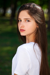 Fototapeta premium Исфдьeautiful brunette girl in white t-shirt on a background of a summer park