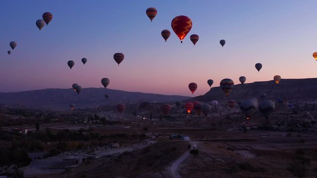 Hot air Balloons light up morning sky in Goreme, Cappadocia. Pullback shot of Turkey Ballooning festival 