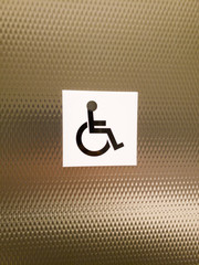 Disability sign with wheelchair on stainless steel wall.