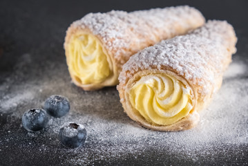 Cream filled horn pastries with blueberries and powdered sugar