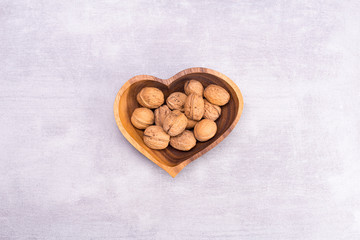 Walnut on a heart-shaped plate on a gray background, top view, flat lay.