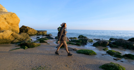 Young female travelr with backpack and retro film camera travel in the autumn mountains near sea	