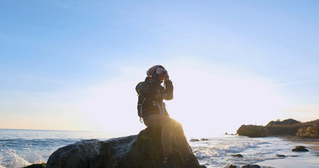 Young female travelr with backpack and retro film camera travel in the autumn mountains near sea	