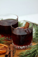 two glasses of mulled wine, cinnamon sticks, orange chips and fir bough on cutting board isolated on white background close up. Flat lay. Vertical image