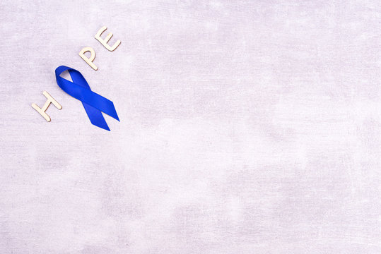 Blue ribbon with the word HOPE, tonic background, colon cancer, colorectal cancer on a gray background with space for text, flat lay, top view