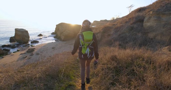 Young female travelr with backpack and retro film camera travel in the autumn mountains near sea