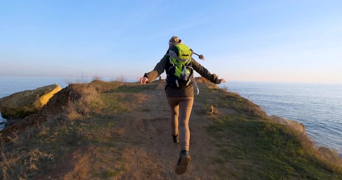 Young female traveler with backpack have fun in the mountains near sea