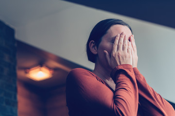 Depressed woman covering face with hands and crying - obrazy, fototapety, plakaty