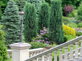 Stairways with stone railings balusters and iron lanterns, landscape design walking path for walking, green lawns and a variety of bushes