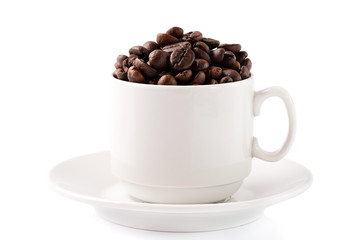 Coffee beans in a white cup on a saucer isolated on white background