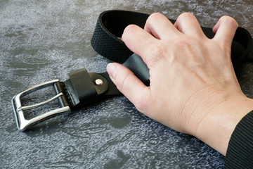 hands with scar clench the belt on black background, psychological trauma concept, violence concept