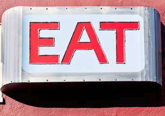 Vintage diner EAT sign mounted on building.