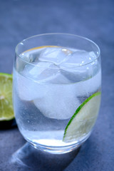  Cold drinking mineral water served in glass with ice cubes and green lime