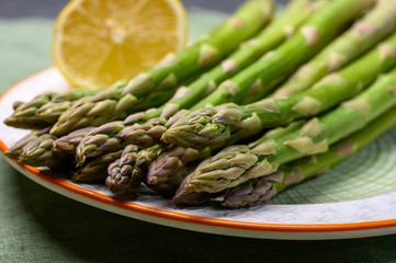 Bunch of fresh green raw organic asparagus with lemon ready to cook