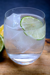  Cold drinking mineral water served in glass with ice cubes and green lime