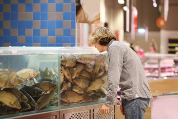 man shopping for fresh fish seafood in supermarket retail store