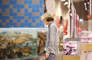 man shopping for fresh fish seafood in supermarket retail store
