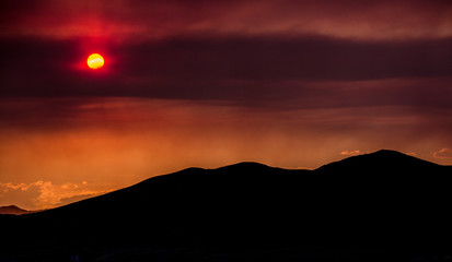 Smoke and clouds from burning wildfires obscures the sun color the sky red before sunset.