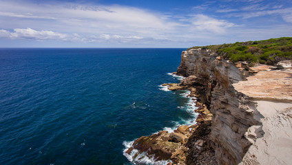 Fototapeta na wymiar Australia's Royal National Park offers spectacular views from rocky cliffs above crashing surf and vibrant blue waters.