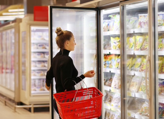 Woman choosing frozen food from a supermarket freezer	