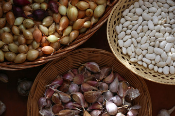 Countryside. Harvest. Top view of small onions, a clove of garlic, white beans in wicker baskets. View from above. Flat lay.  