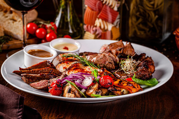 Turkish cuisine. Assorted different meat on the grill, lamb, chicken, pork with grilled vegetables. Serving dishes in a restaurant on a white plate. background image, copy space