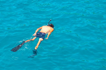 Man swims in the sea with a snorkel and a mask, diving.