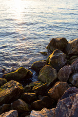 Rocks on beach by the sea at the sunset 