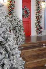 snow-covered porch of a house decorated by Christmas with a red door