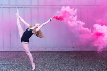 Teenage ballet dancer with colorful red smoke bomb