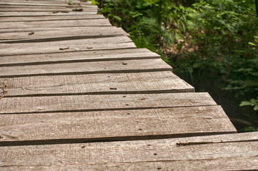 Small weathered wooden boards bridge over river waters closeup