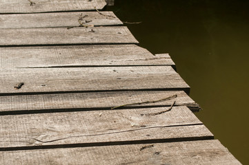 Small weathered wooden boards bridge over river waters closeup