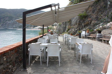an all white or light colored luxury restaurant set on elegant tables on a terrace overlooking the sea in the Cinque Terre in Monterosso