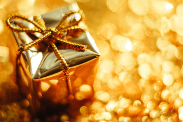 Golden gift on defocused lights background close up.