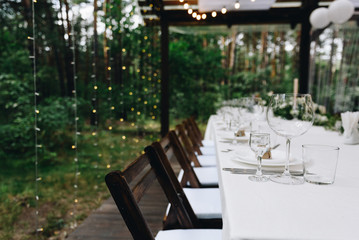 Long table for guests set up for a beautiful wedding outdoors in a tent or a pavilion