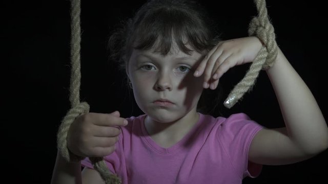 Child under supervision. The child is a puppet. Sad little girl with her hands tied like a puppet.