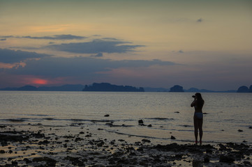 Naklejka premium Jeune femme photographiant un coucher de soleil en Asie