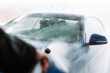 Man washing his car in car wash self service shop. Car maintenance concept