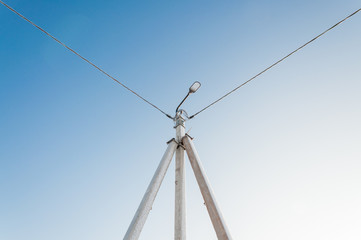Electric pole on blue sky background during sunrise.