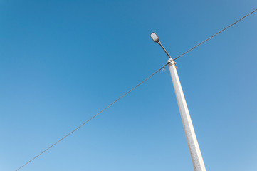Electric pole on blue sky background during sunrise.