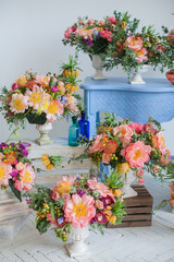Workshop on creating a bouquet and floral arrangements from different plants in the style of boho chic. Pink peonies, red roses, green eucalyptus. Bouquets in ceramic wooden coasters. For weddings.