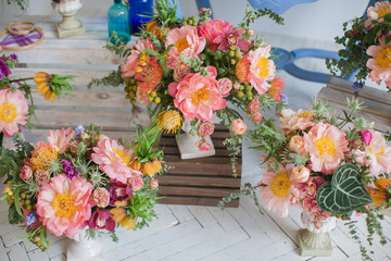 Workshop on creating a bouquet and floral arrangements from different plants in the style of boho chic. Pink peonies, red roses, green eucalyptus. Bouquets in ceramic wooden coasters. For weddings.