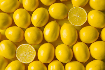 Top view many ripe lemons on a yellow surface, background or concept